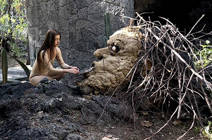 still from 'concrete shape' by jesi jordan- featuring a figure sculpting a large head out of clay in a forest environment